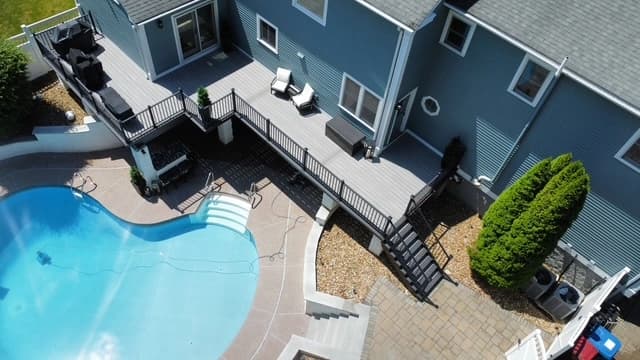 Aerial view of composite deck with stairs adjacent to a kidney-shaped in-ground pool