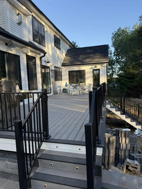 Composite deck walkway with black aluminum railing overlooking a wooded backyard